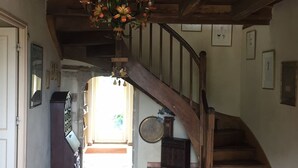 Una escalera de madera que lleva a un segundo piso, un candelabro y un cartel de bienvenida.