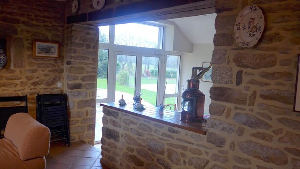Una habitación de paredes de piedra con un gran ventanal, una chimenea y un sillón de cuero.