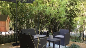 Eine Holzterrasse mit Gartenmöbeln, umgeben von Bambus und anderer Vegetation.