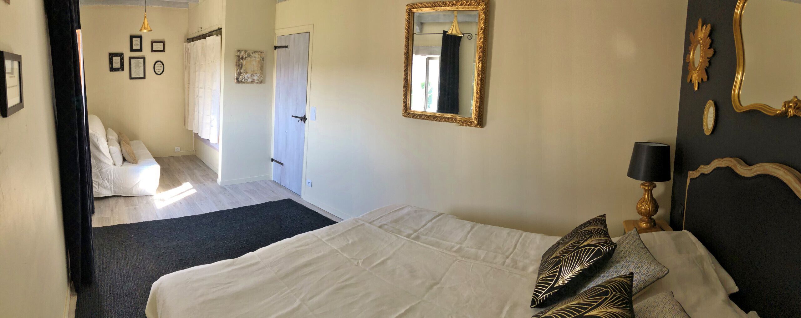 Une chambre à coucher comprenant un lit, une table de chevet avec une lampe, un miroir et une porte donnant sur une autre pièce.