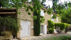 A stone building with a white door, a small garden with lavender, and a stone wall.