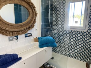 A bathroom with a white sink, a mirror with a rope frame, a blue towel, and patterned tiles.