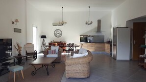 Ein geräumiges Wohnzimmer mit einer Couch, einem Esstisch und einer Küche im Hintergrund.