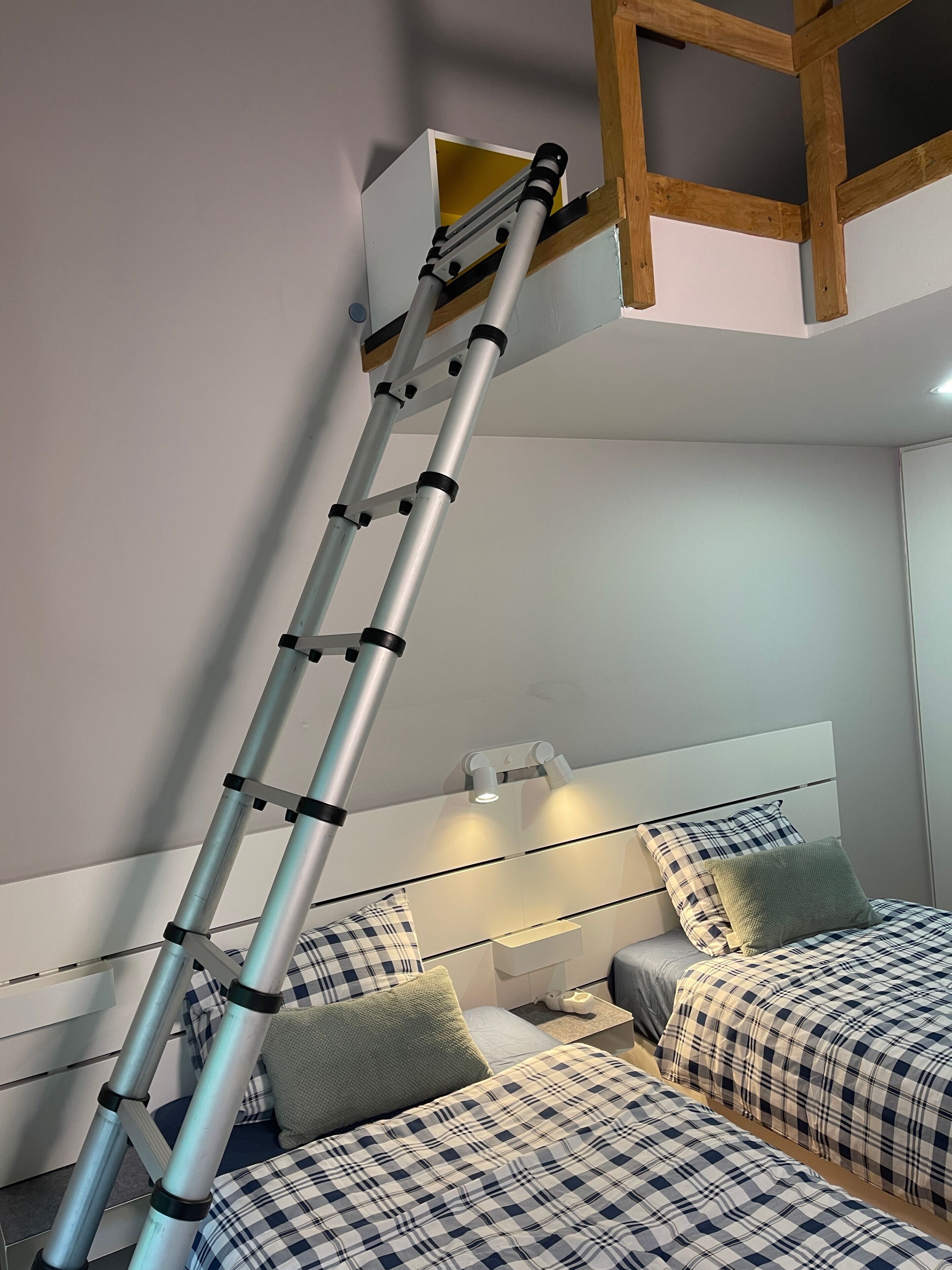 Een ladder in een kamer met een bed en een hoofdbord met verlichting.