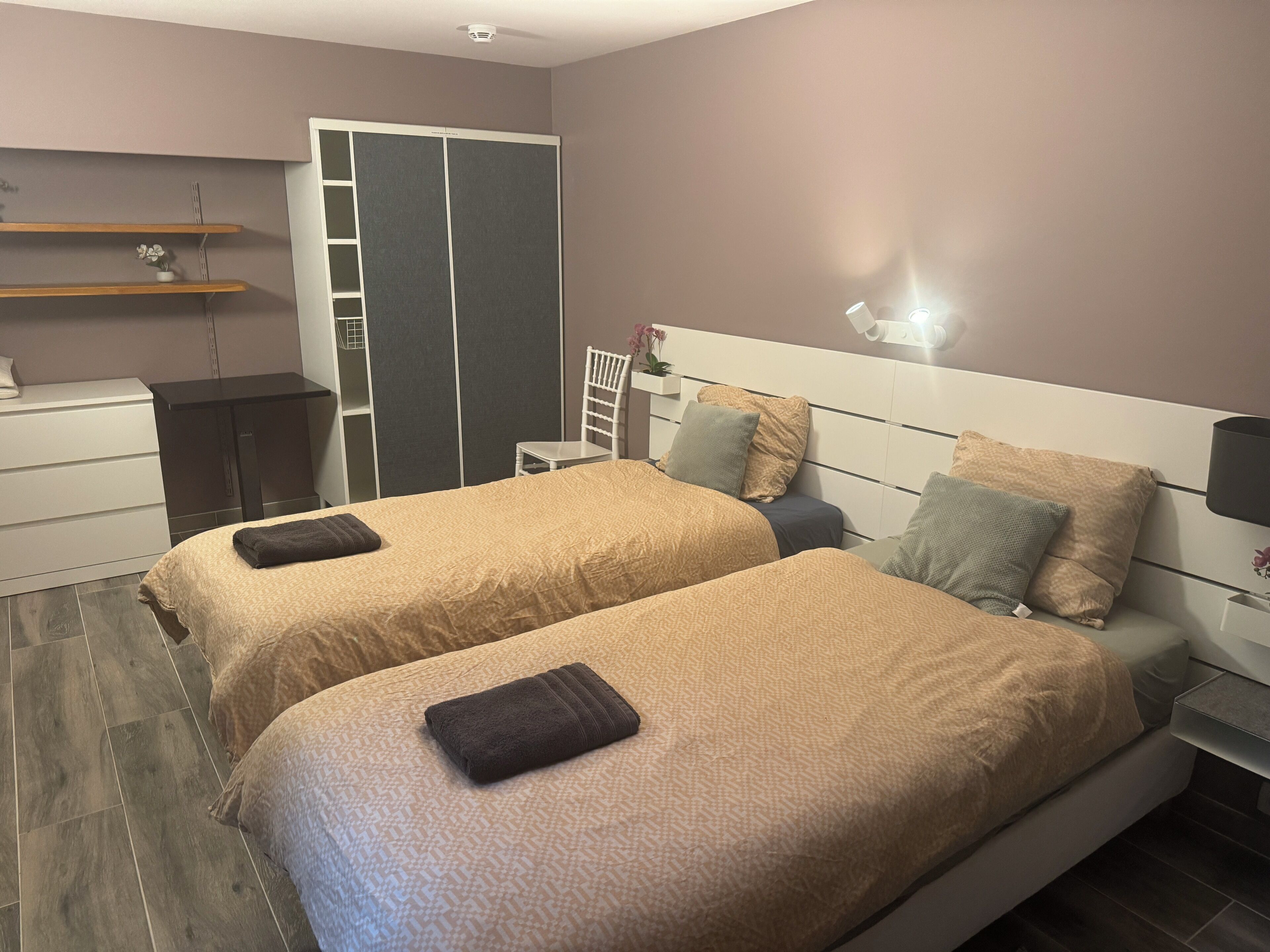 Un dormitorio moderno con dos camas, un armario, un escritorio y una silla.