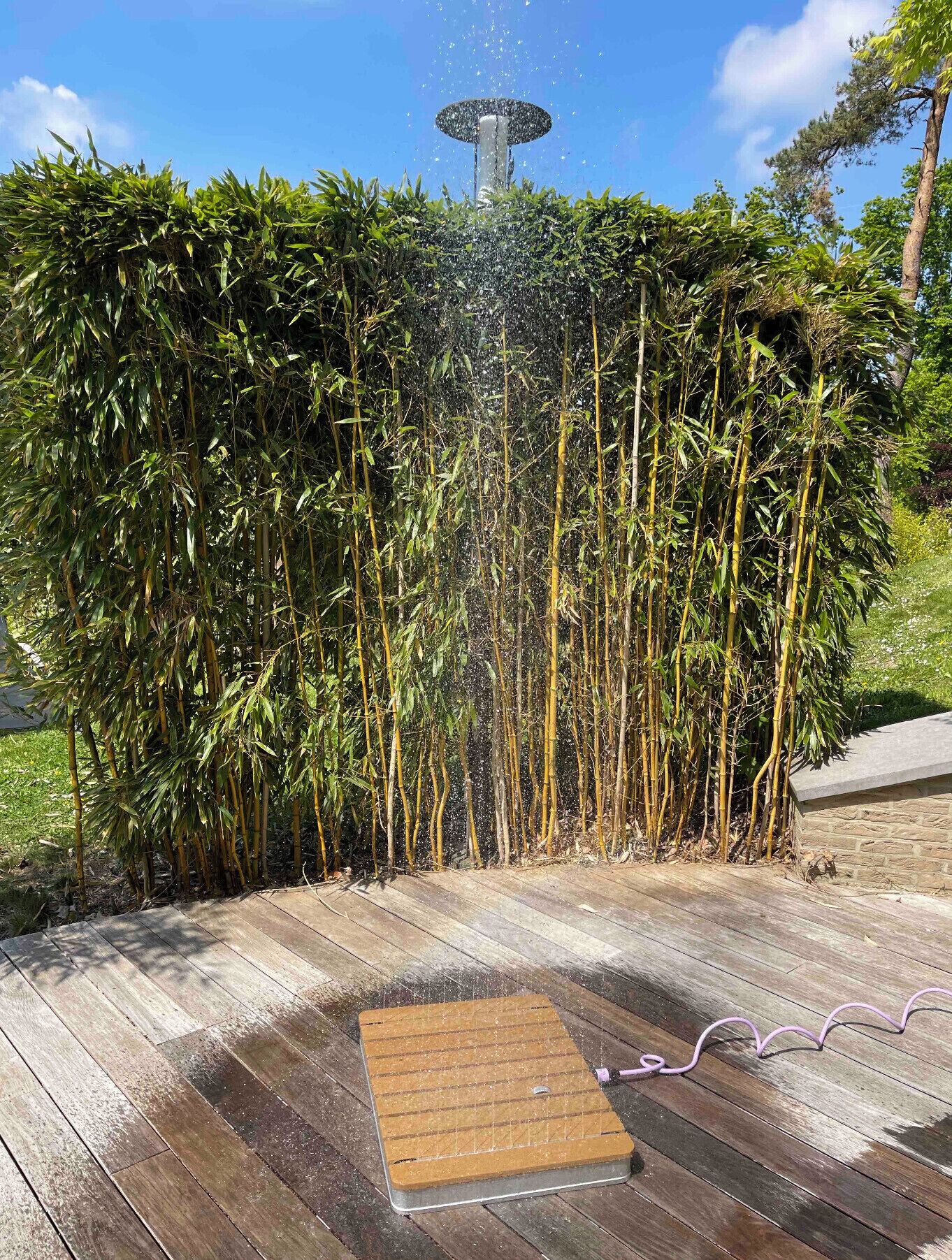 A wooden deck with a square mat and a garden hose.