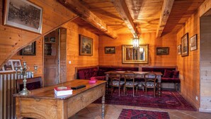 A wooden interior with a wooden bench, a table with chairs, and a chandelier. - 🌟Parenthèse nature en Auvergne: Maison typique au panorama exceptionnel-10 pers (saint- sauves d'Auvergne)