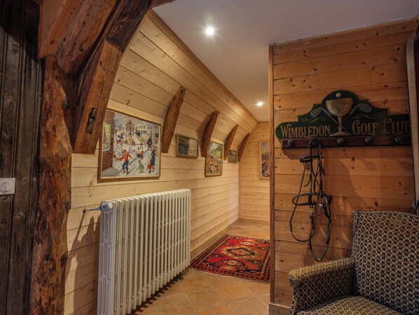 Un interior de madera con un radiador, un tapete rojo estampado y un cartel que indica 'Wimbledon Golf Club'.