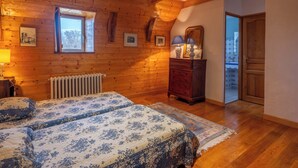 A cozy bedroom with wooden walls, a large bed, a dresser, and a window. - 🌟Parenthèse nature en Auvergne: Maison typique au panorama exceptionnel-10 pers (saint- sauves d'Auvergne)