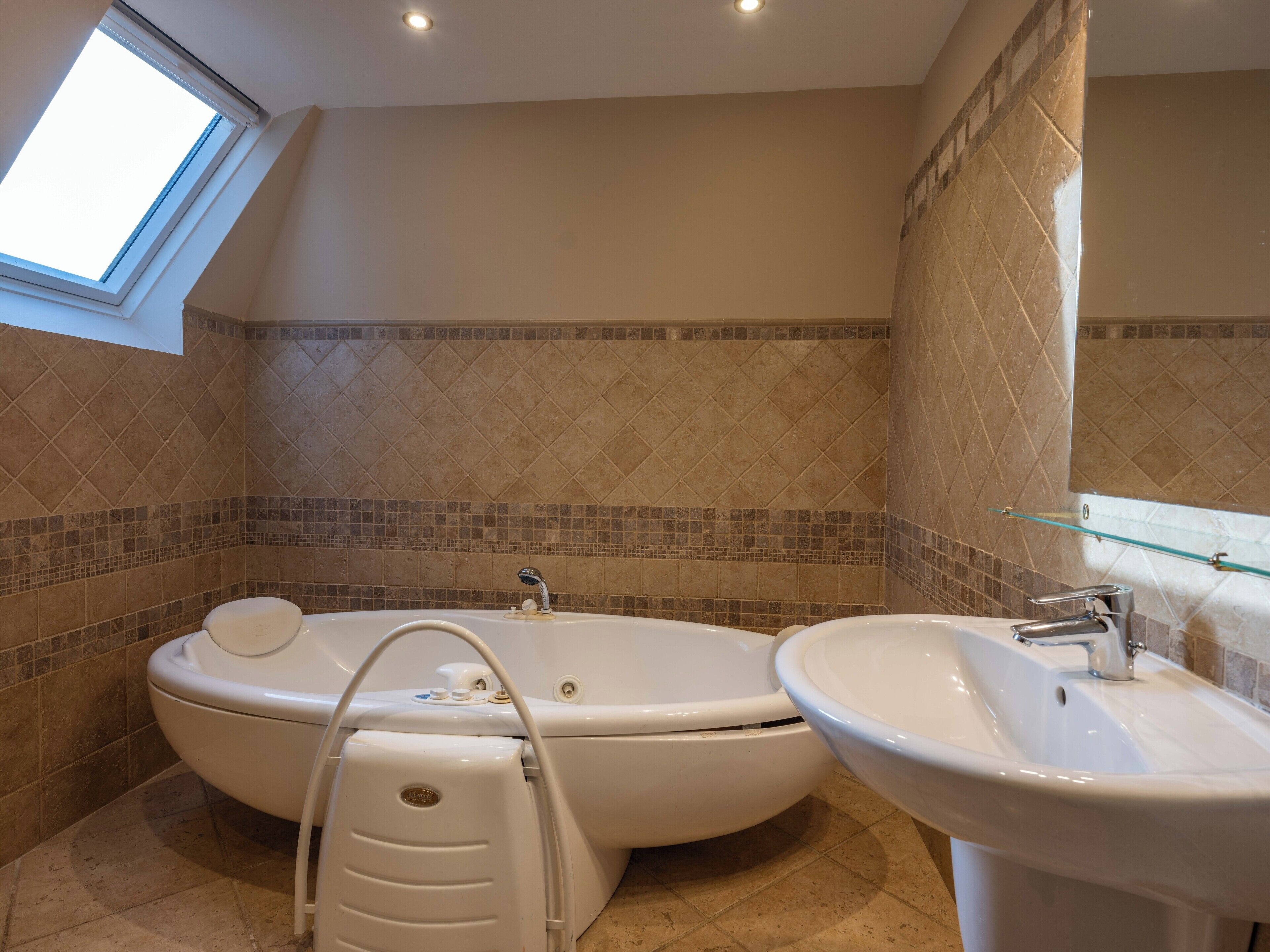 Un baño con bañera independiente, lavamanos y ventana que proporciona luz natural.