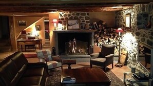 A cozy living room with a fireplace, stone walls, and a staircase leading upstairs. - 🌟Parenthèse nature en Auvergne: Maison typique au panorama exceptionnel-10 pers (saint- sauves d'Auvergne)