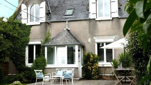 A house with a wooden deck, a conservatory, and a garden with chairs and plants. - Village house Scandinavian charm (Carantec)