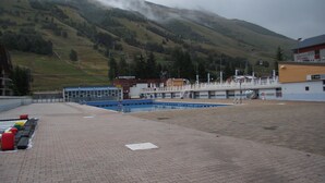 Un espace piscine avec vue sur une montagne et un bâtiment sur lequel est apposée une enseigne indiquant « B&B PIZZERIA ».