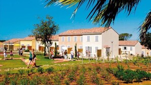 Zona residencial con casas, un jardín y personas caminando.