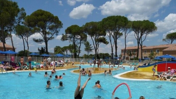 Un área de piscina con varias piscinas, sillas de descanso y sombrillas.