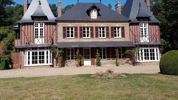 A large, two-story house with a symmetrical facade, multiple chimneys, and a central entrance with a covered porch. - Manoir du Chambellan (Les Baux-Sainte-Croix)