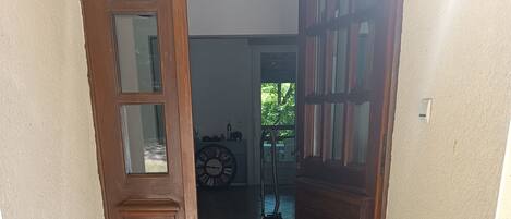 Un pasillo con puerta de madera, piso de baldosas y una alfombra pequeña.