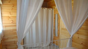 A wooden cabin room with a bed, white curtains, and a metal railing. - In Mimizan-plage sud, small wooden house facing the forest, 2km from the ocean  (Mimizan)