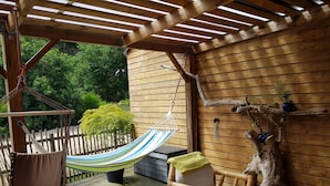 A wooden deck with a hammock, a chair, and a table. - In Mimizan-plage sud, small wooden house facing the forest, 2km from the ocean  (Mimizan)