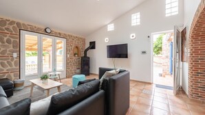 Amplia sala de estar con pared de piedra, un sofá de cuero negro, un televisor y una chimenea de piedra.