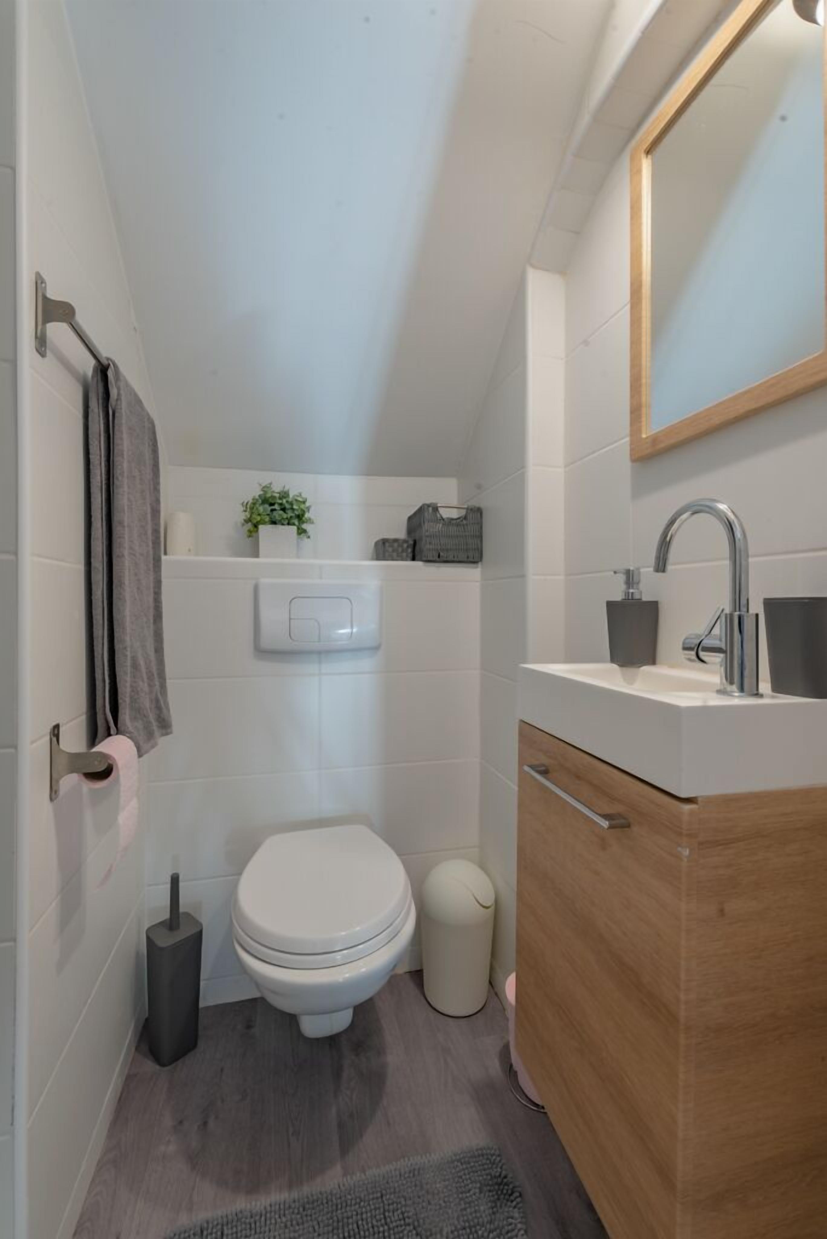 Un baño moderno con inodoro, lavamanos y espejo.