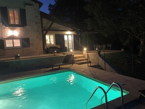 En swimmingpool med klar kant, en liggestol og en trappe til en overdækket terrasse.