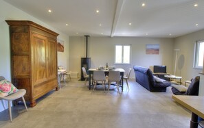 Uma sala ampla com uma mesa de jantar, sofá e um grande armário de madeira.