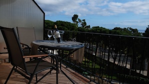 Ein Balkon mit Tisch und Stühlen, einer Champagnerflasche und einem Glas Wasser.