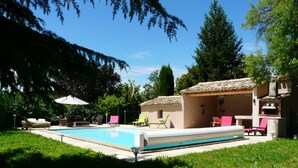 Una piscina con sillones de descanso y zona de barbacoa.