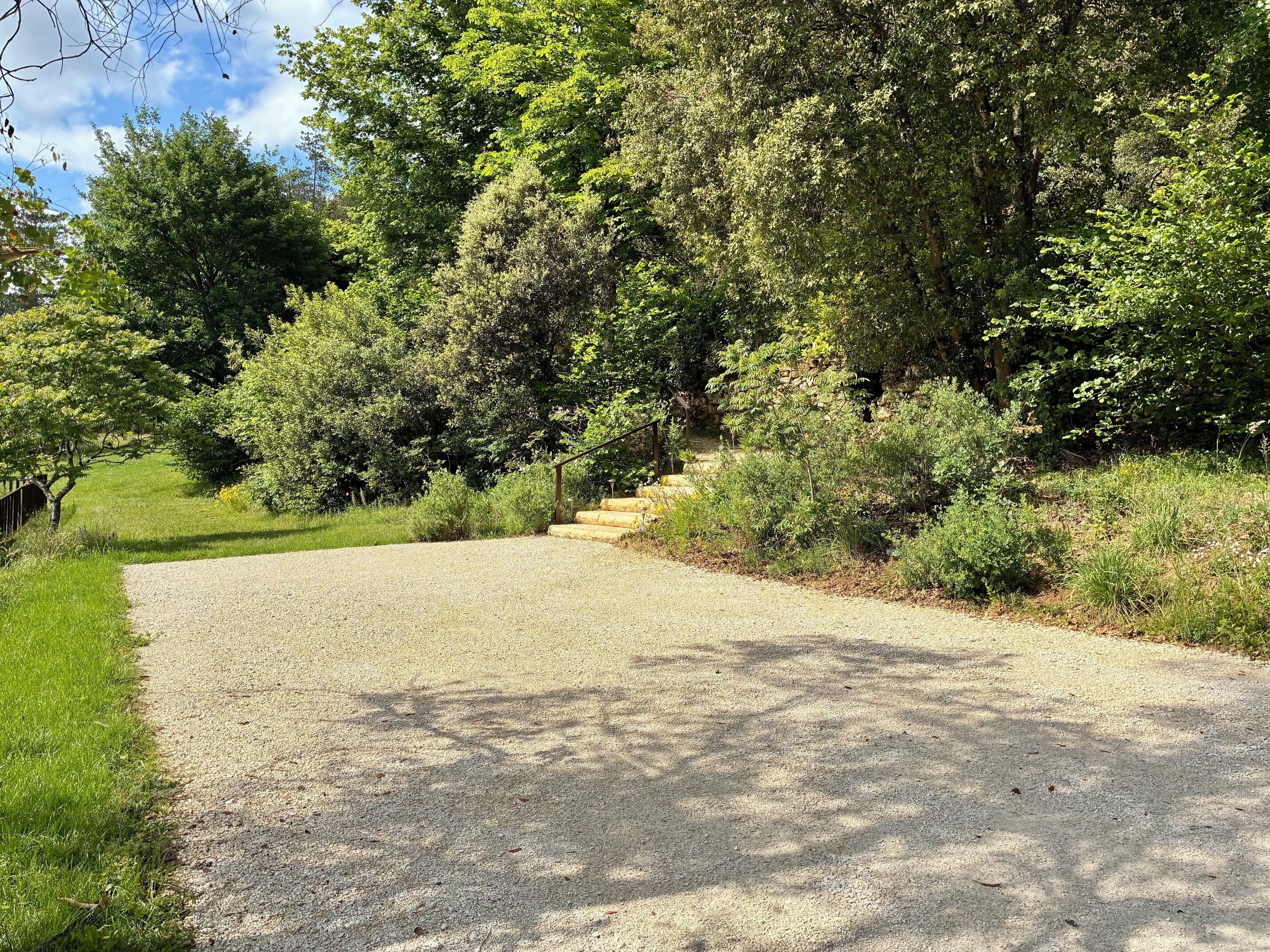 A gravel path leading through a wooded area with a stone staircase.