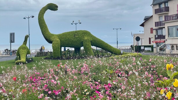 A dinosaur-shaped topiary in a flower garden with a building in the background. - Charming apartment in the city center of 63 m2 (Villers-sur-Mer)