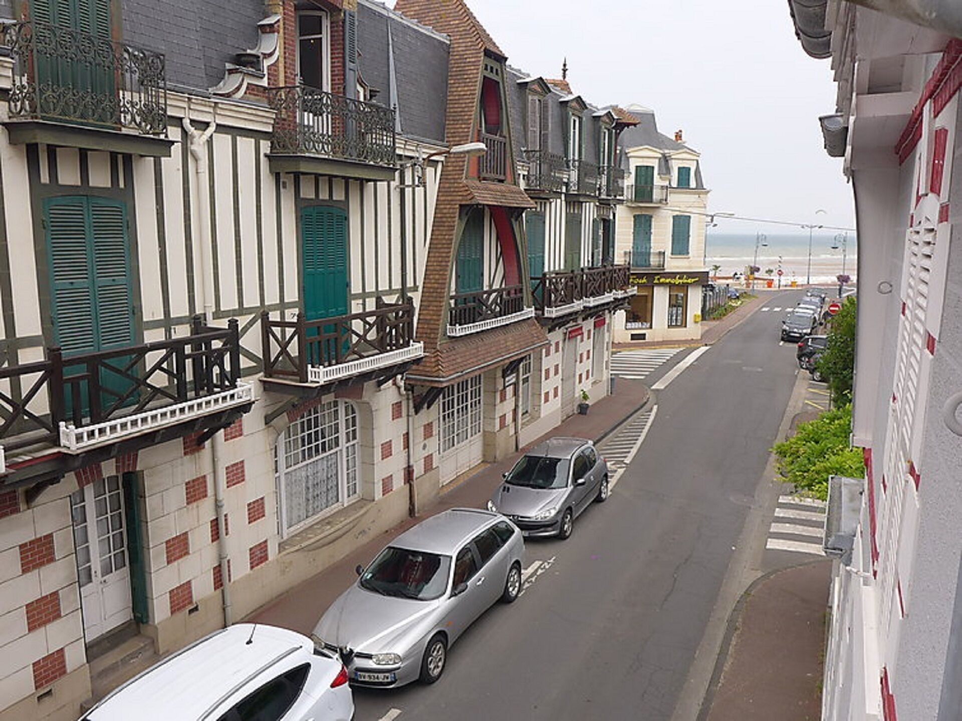 Una calle estrecha flanqueada por edificios de varios pisos, con balcones y contraventanas.