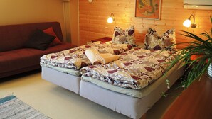 A cozy bedroom with a large bed, a red sofa, and a wooden wall.