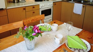 A kitchen with wooden cabinets, a stove, a microwave, and a sink. There is a table with a vase of flowers, a plate, and a napkin.