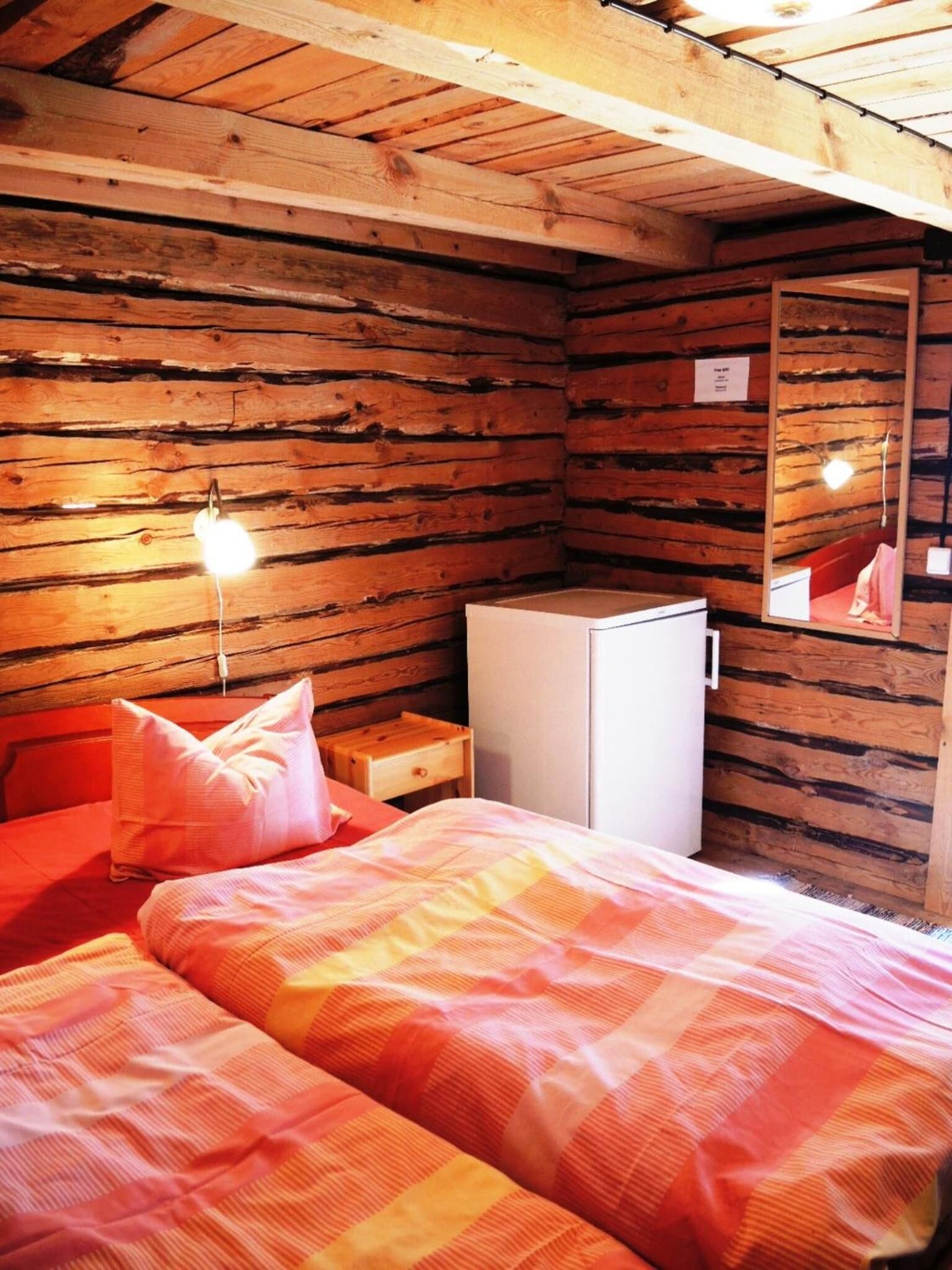 Una habitación acogedora de estilo cabaña con dos camas, una mesita de noche de madera, un aparador blanco y un espejo en la pared.