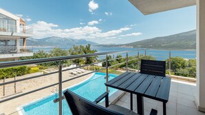 En balkong med pool, utemöbler och utsikt över havet och bergen.