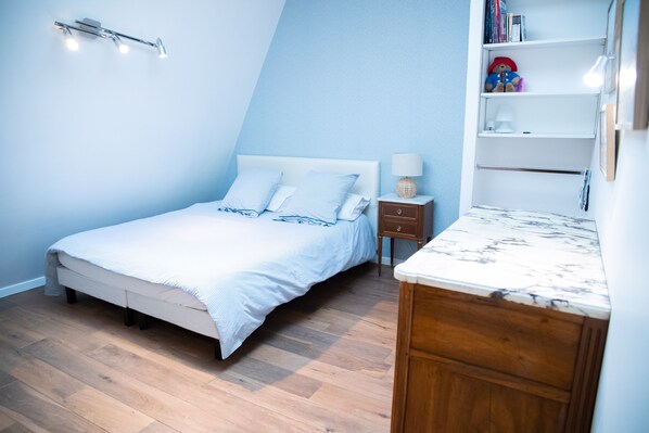 Ein Schlafzimmer mit einem Bett, Nachttisch, Regalen und Büchern sowie einem Spielzeug.