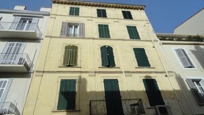 Un immeuble à plusieurs étages doté de balcons, de volets verts et de climatiseurs.