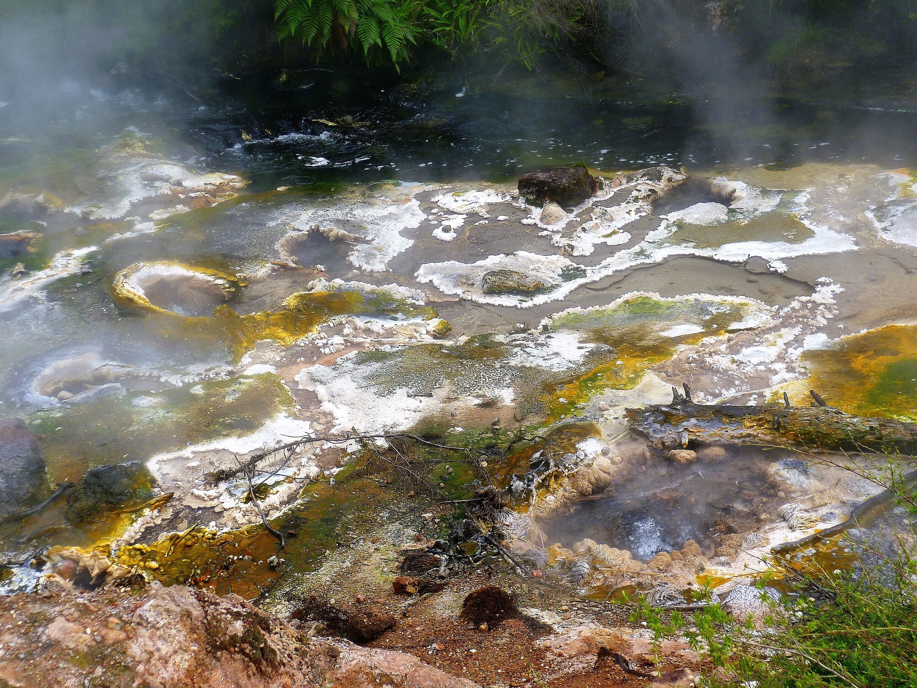 Un área geotérmica con depósitos minerales y vapor saliendo del suelo.
