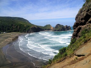 A coastal landscape with a beach, waves, and rocky cliffs.