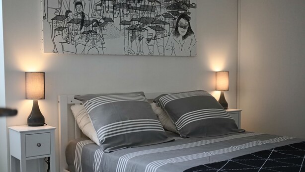 Ein Schlafzimmer mit einem Bett, zwei Nachttischen, zwei Lampen und einem Wandbild.