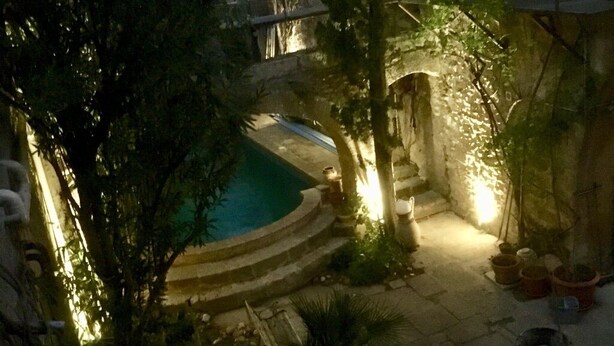 A courtyard with a swimming pool, stone steps, and potted plants.