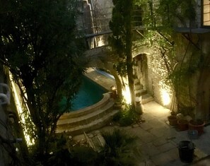 A courtyard with a swimming pool, stone steps, and potted plants.