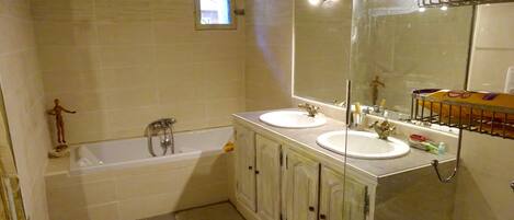 A bathroom with two sinks, a bathtub, and a large mirror.