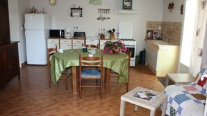 A compact kitchen with a dining area, a small table, and a sofa. - GITE LACCALMIE 17 - MATHE BRILLOUET CLAUDINE ET PATRICE (Saintes)