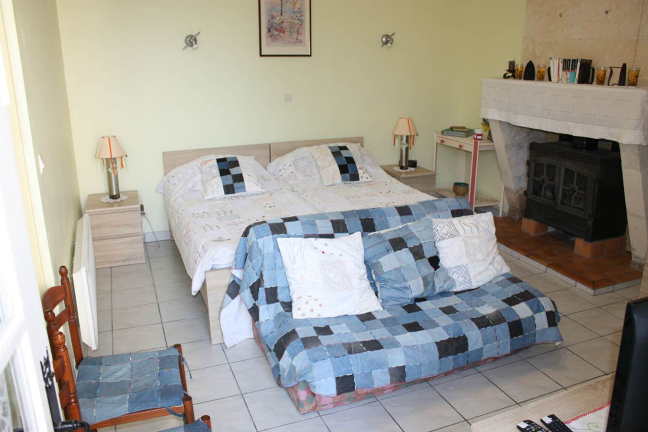 Un dormitorio con cama, una silla, una mesita de noche, una lámpara y una chimenea.