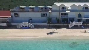 A beachfront property with a two-story building, a staircase leading to the beach, and a clear view of the ocean.