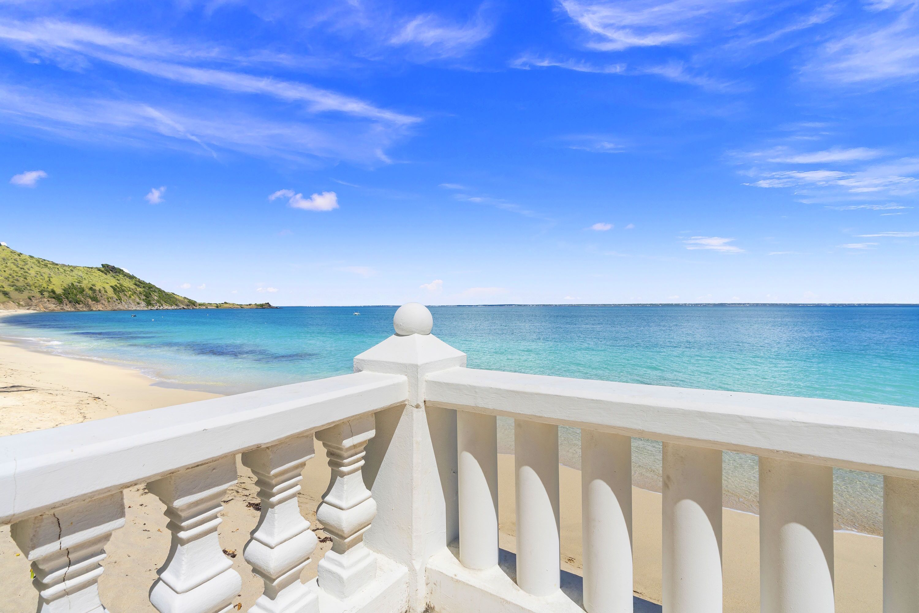 Une plage avec une balustrade blanche et un ciel d’un bleu limpide.