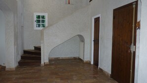 A staircase with stone steps leading to a landing, a wooden door, and a small window with a view of greenery.