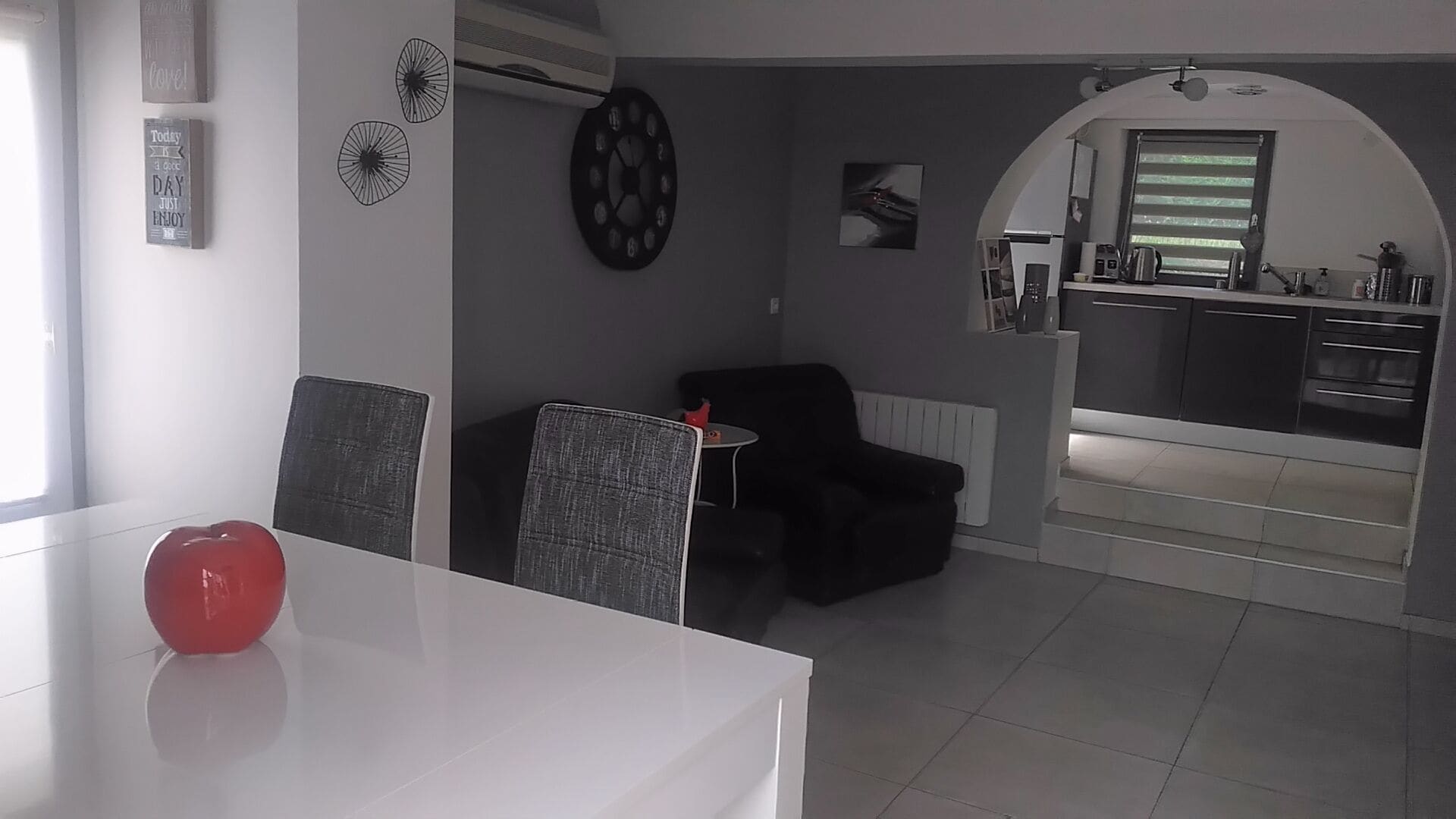 Une cuisine moderne avec un coin repas, une petite table et un objet rouge posé sur la table.